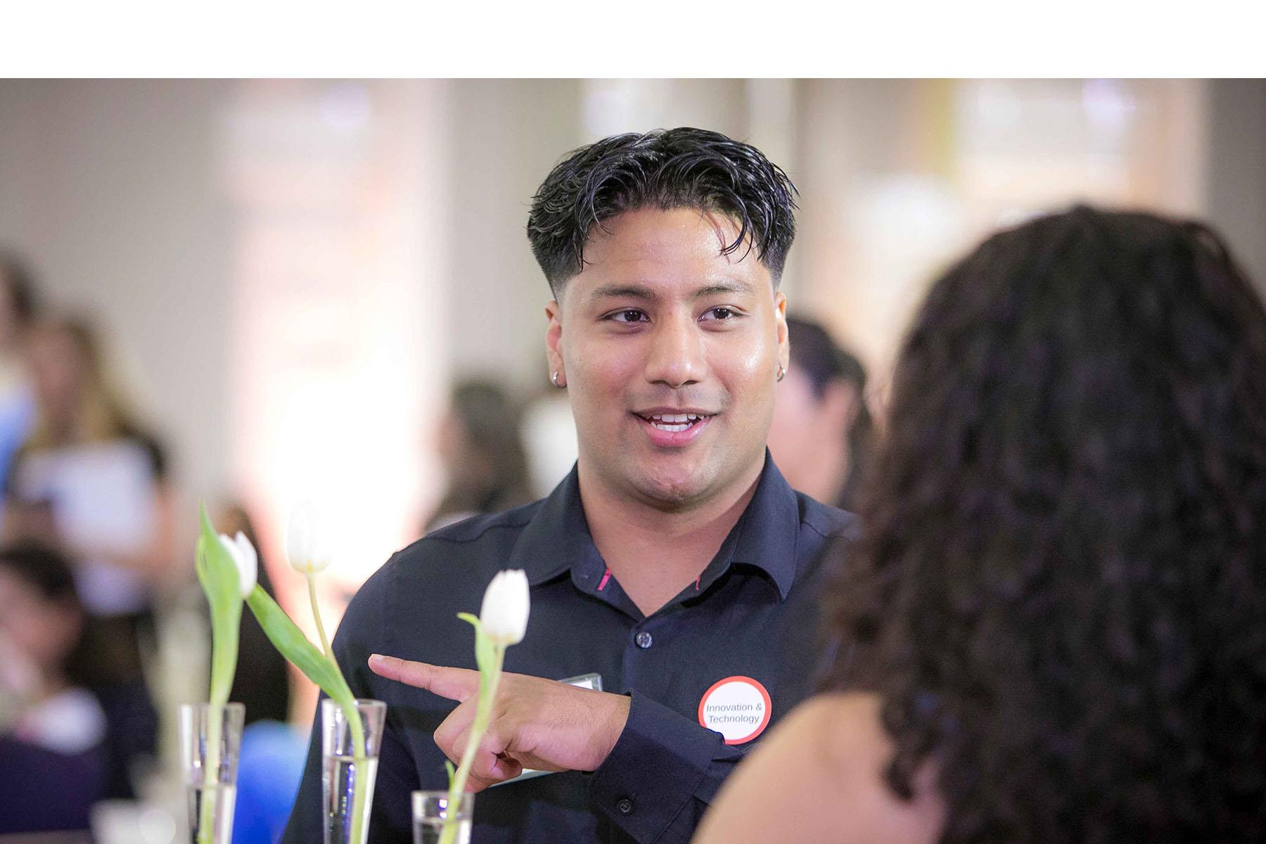Two event attendees talking together at a table in the reception area.