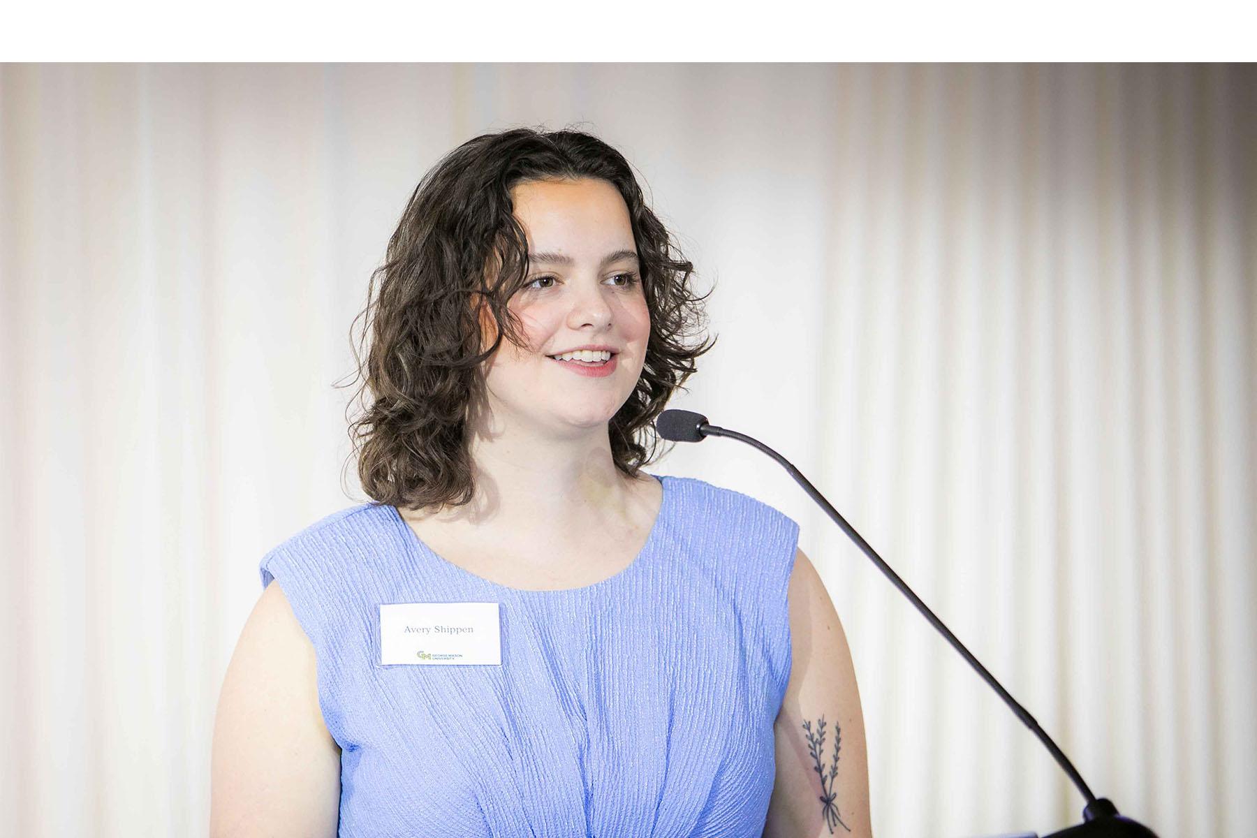 Event speaker addresses attendees on stage at a podium.
