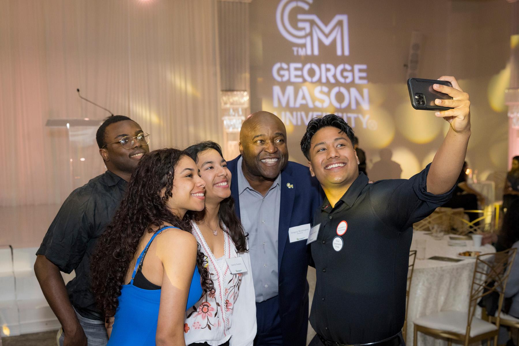 President Gregory Washington taking a selfie with four students in the reception area.