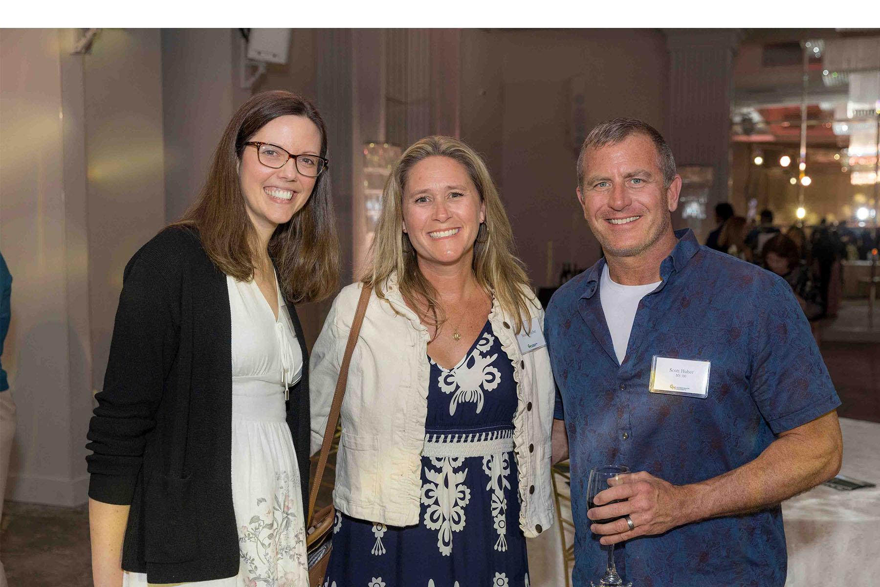 Three event attendees standing together in the reception area.