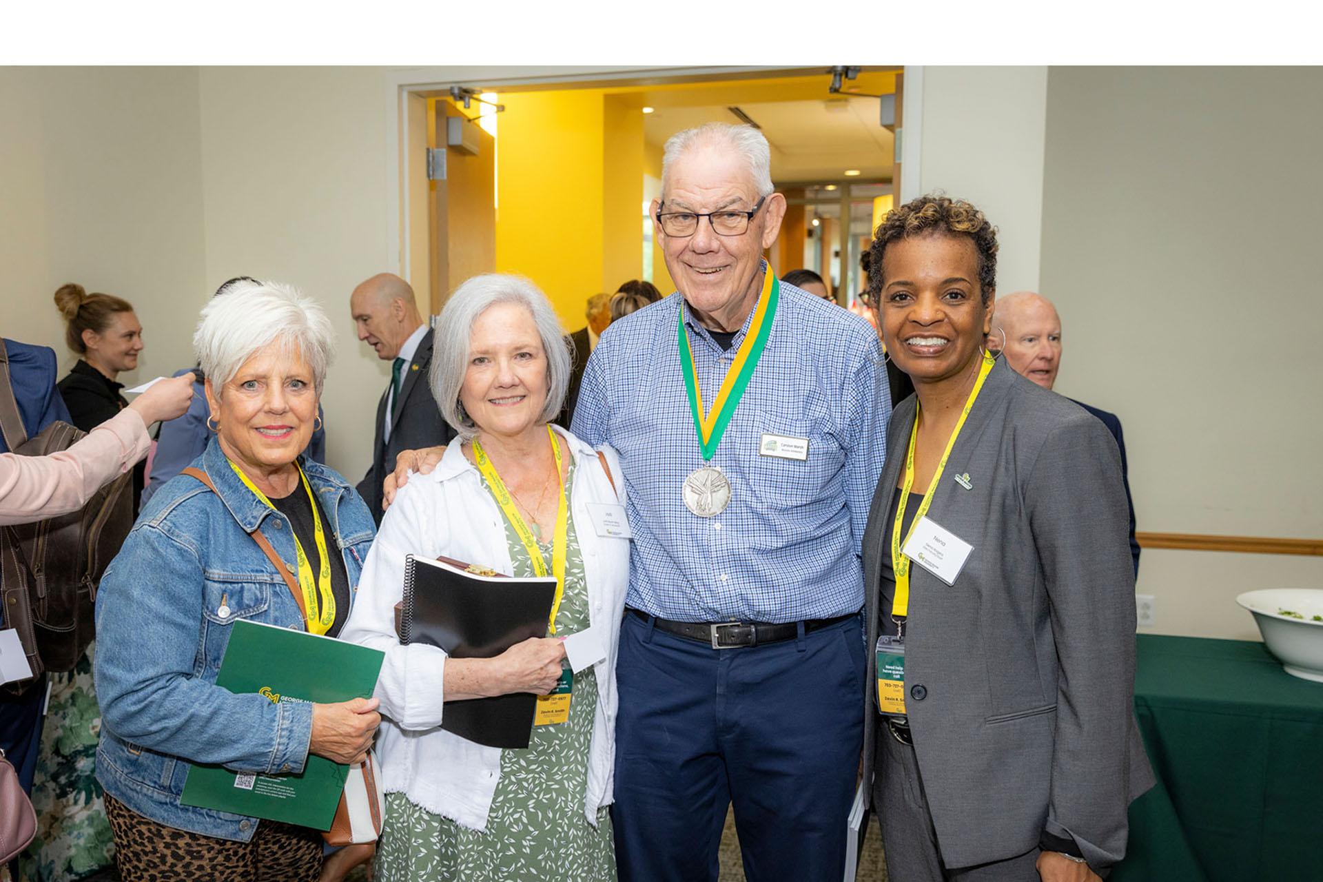 Two event attendees posing with Jay Marsh and Nena Rogers in a reception room.