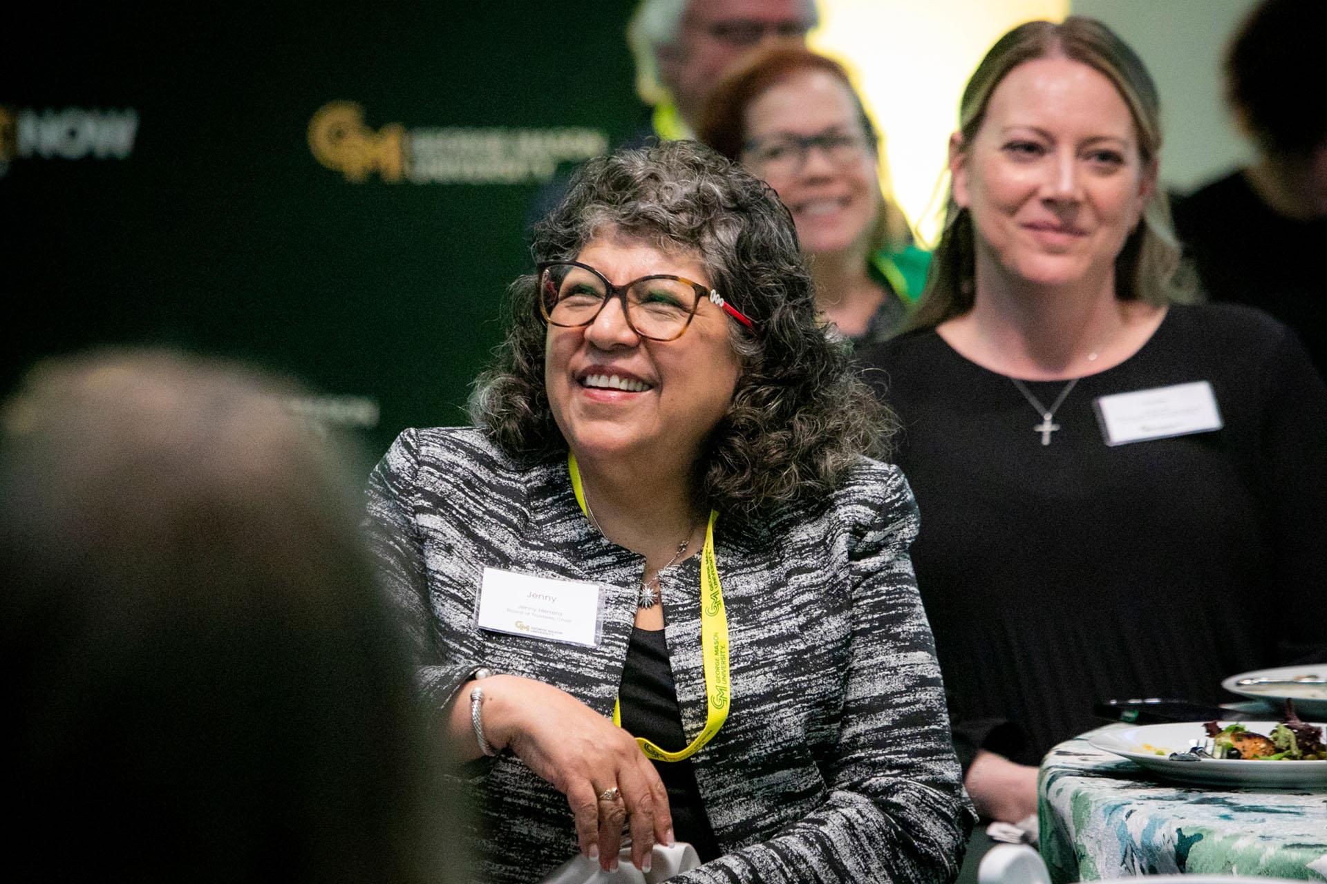 Jenny Herrera seated with event attendees in a reception room.
