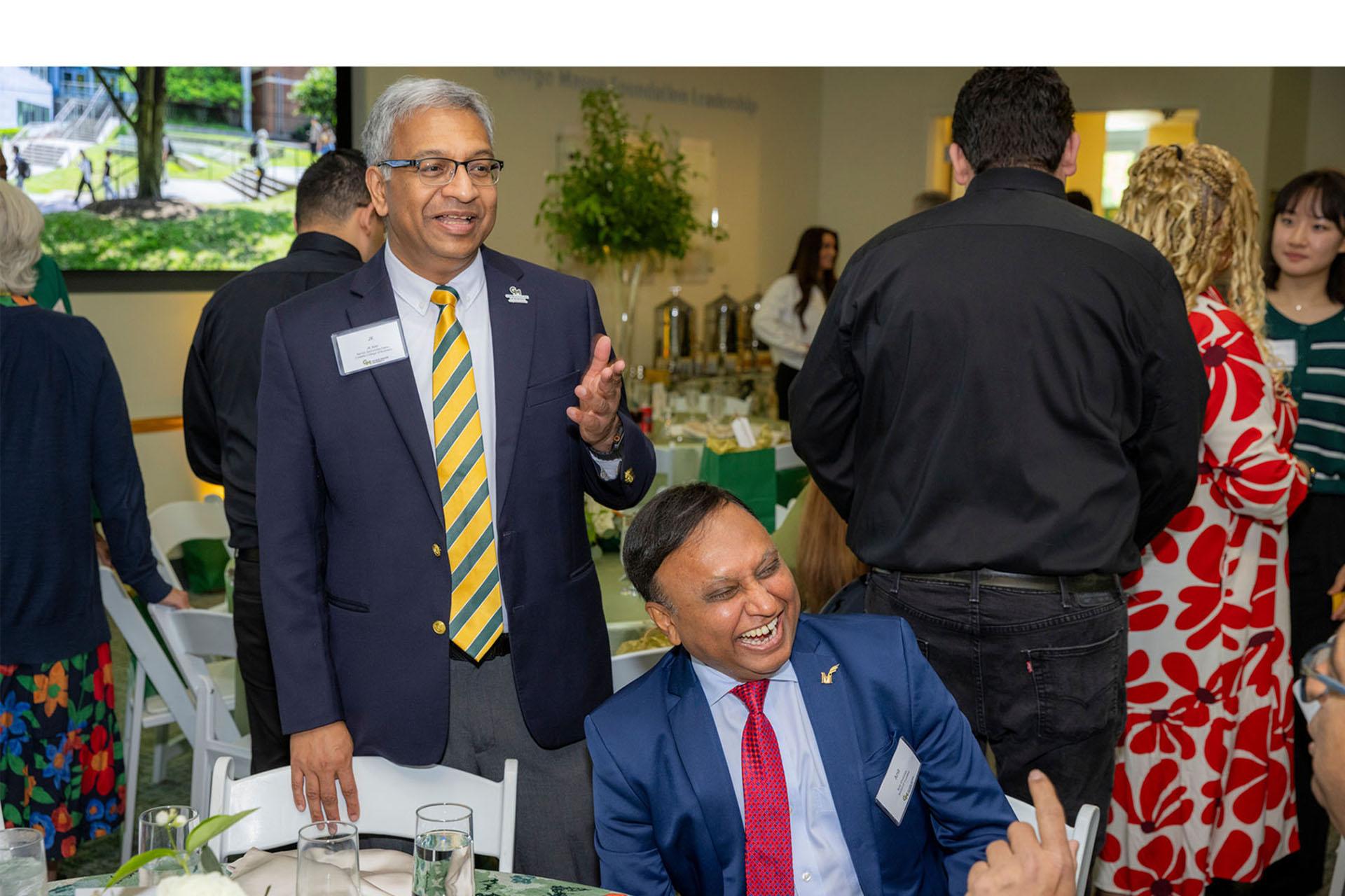Event attendees speaking together around a table in a reception room.