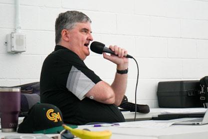 Chris Coneeney seated at a table with a microphone.